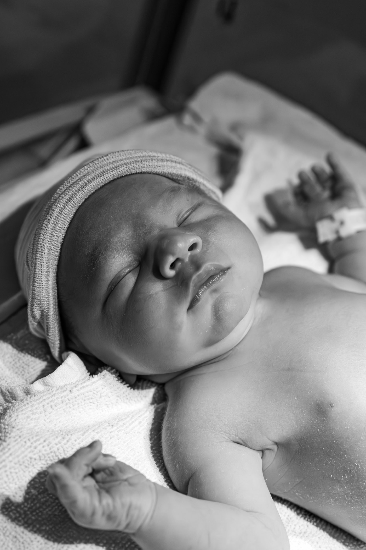 En noir et blanc, un nouveau-né endormi coiffé d'un petit bonnet de coton