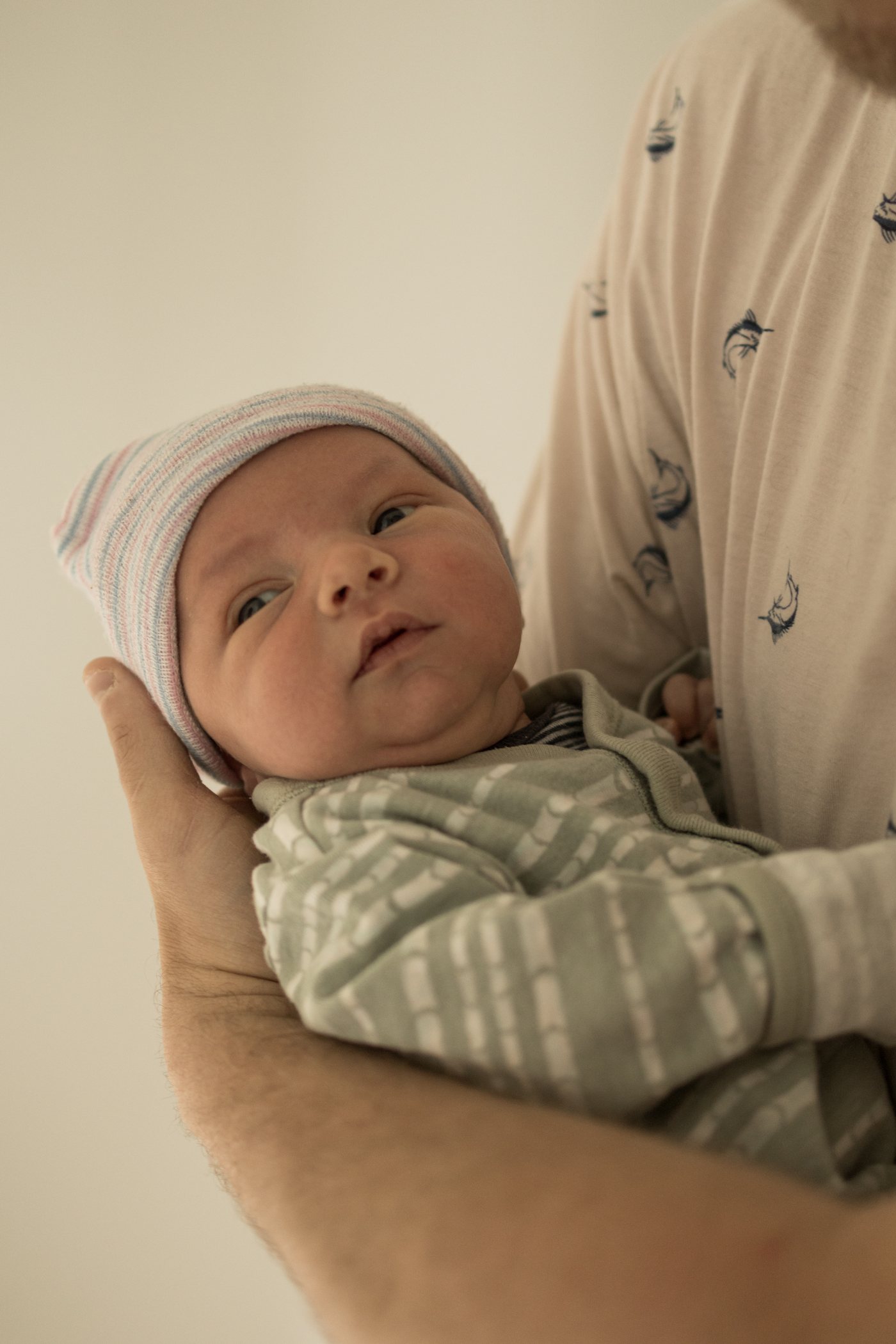 Nouveau-ne au petit bonnet, tenu dans deux mains