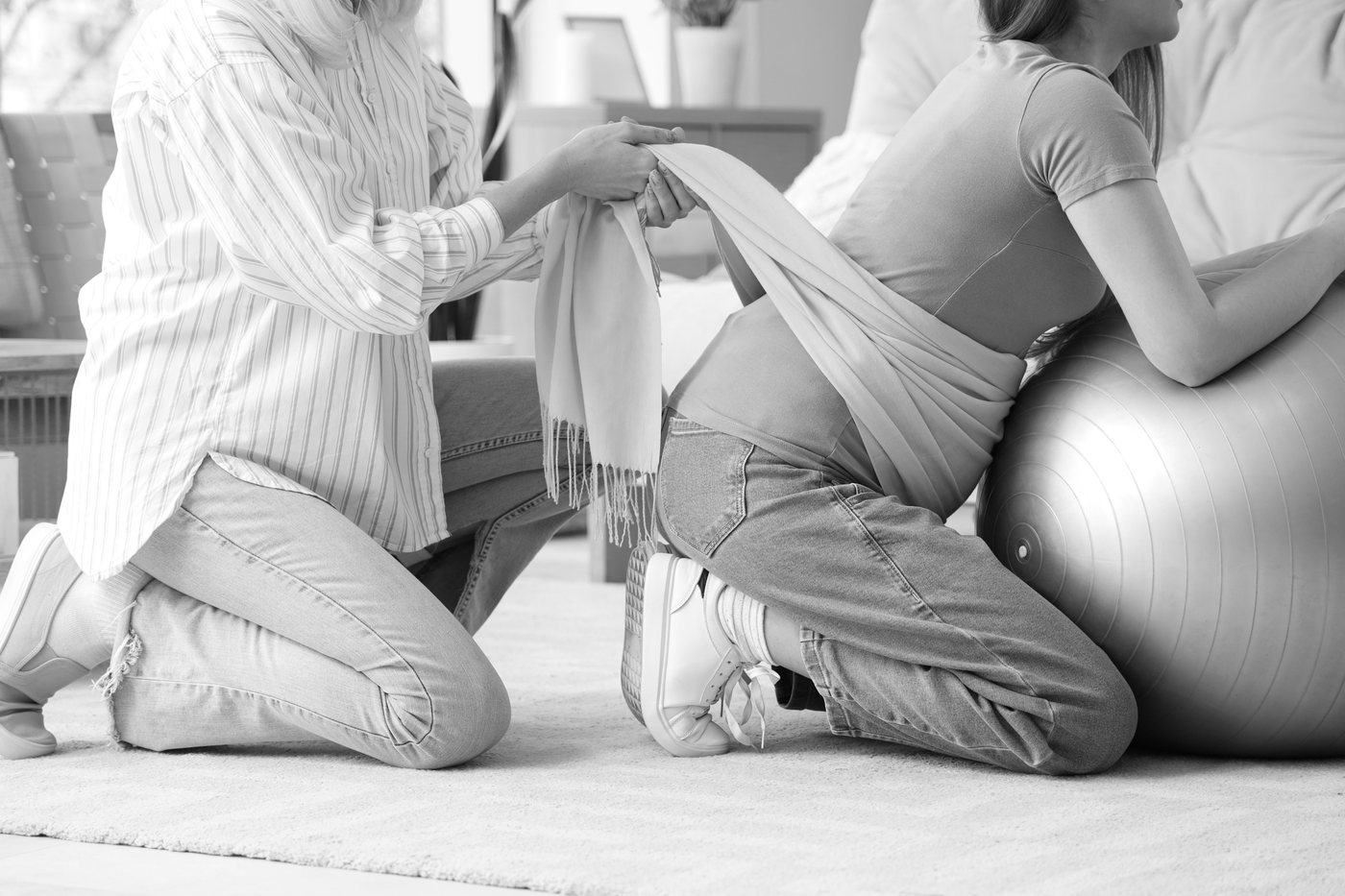 Anne-Sophie enveloppe le ventre d'une femme dans un rebozo, en noir et blanc