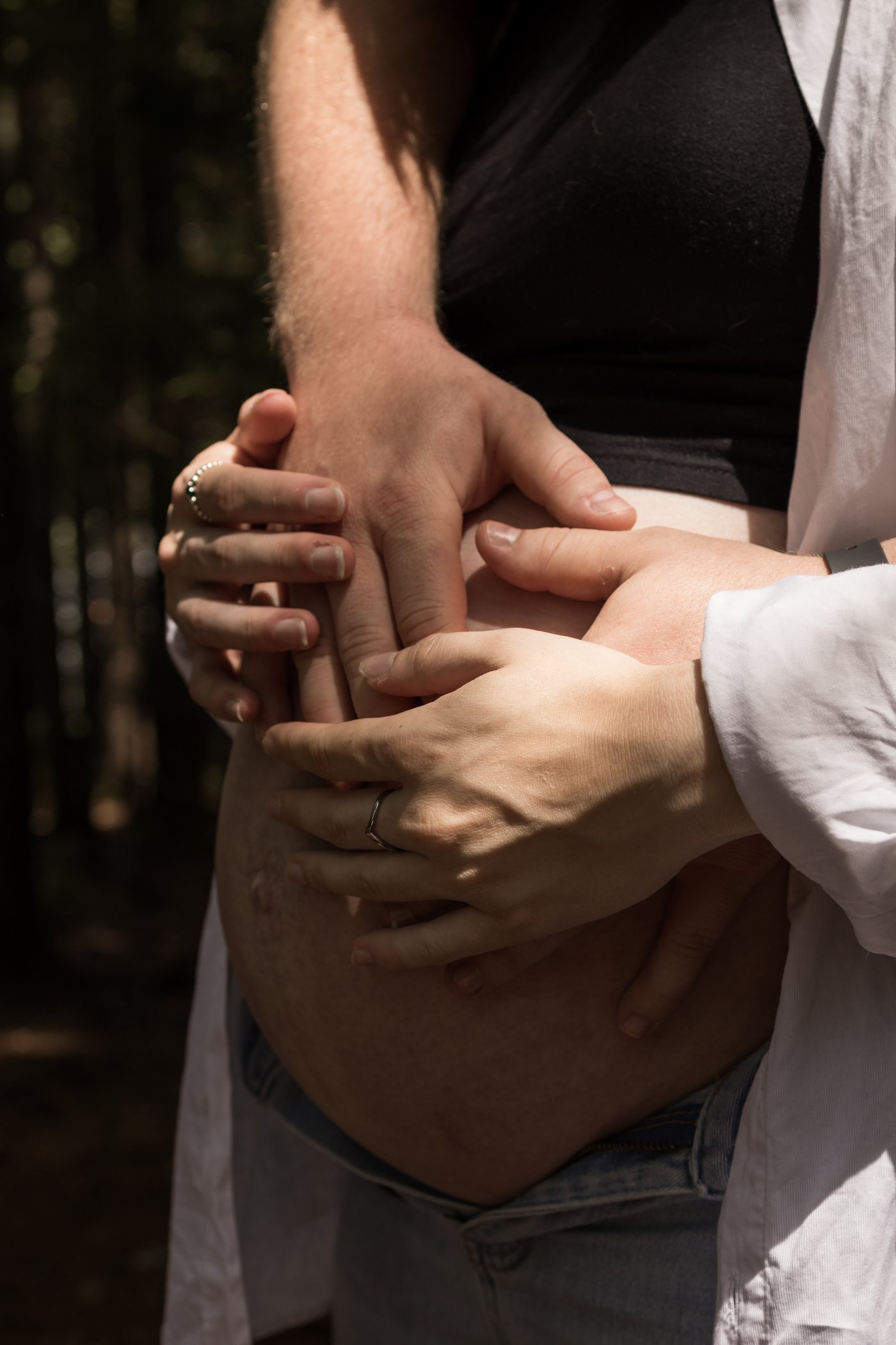 Les mains d'un couple posées ensemble sur le ventre rond de la future maman